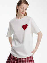A lady wears a white T-shirt with a plaid skirt.